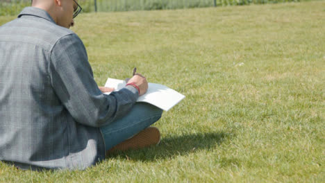 Handheld-Shot-of-a-Student-Writing-Notes-In-Park